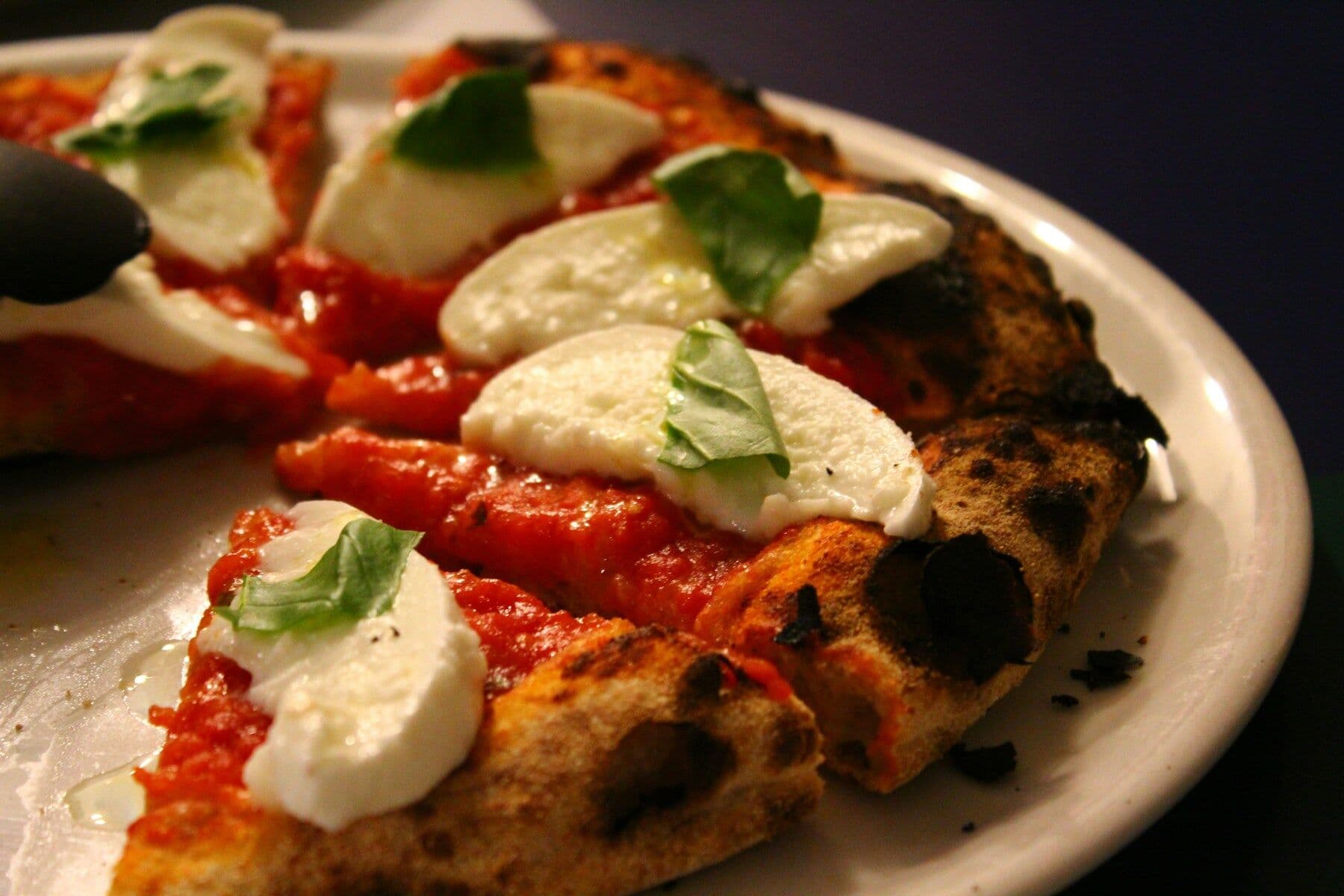 A margherita pizza on a plate, lit low