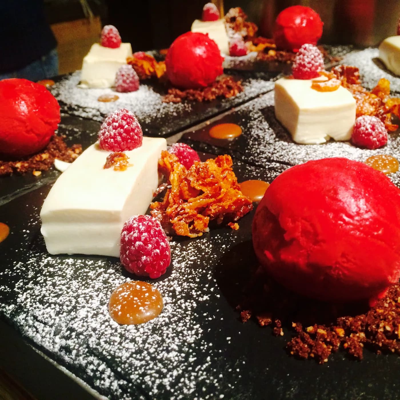 Panna cotta with raspberry sorbet, honeycomb and raspberries on slate