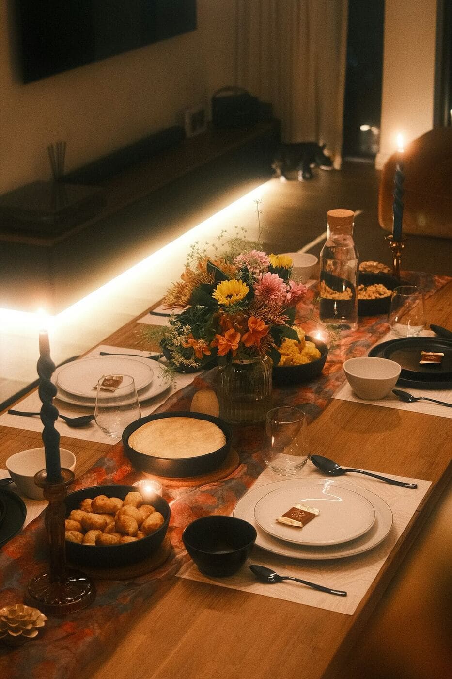 A long table set with plates, candles and flowers before anyone sits down