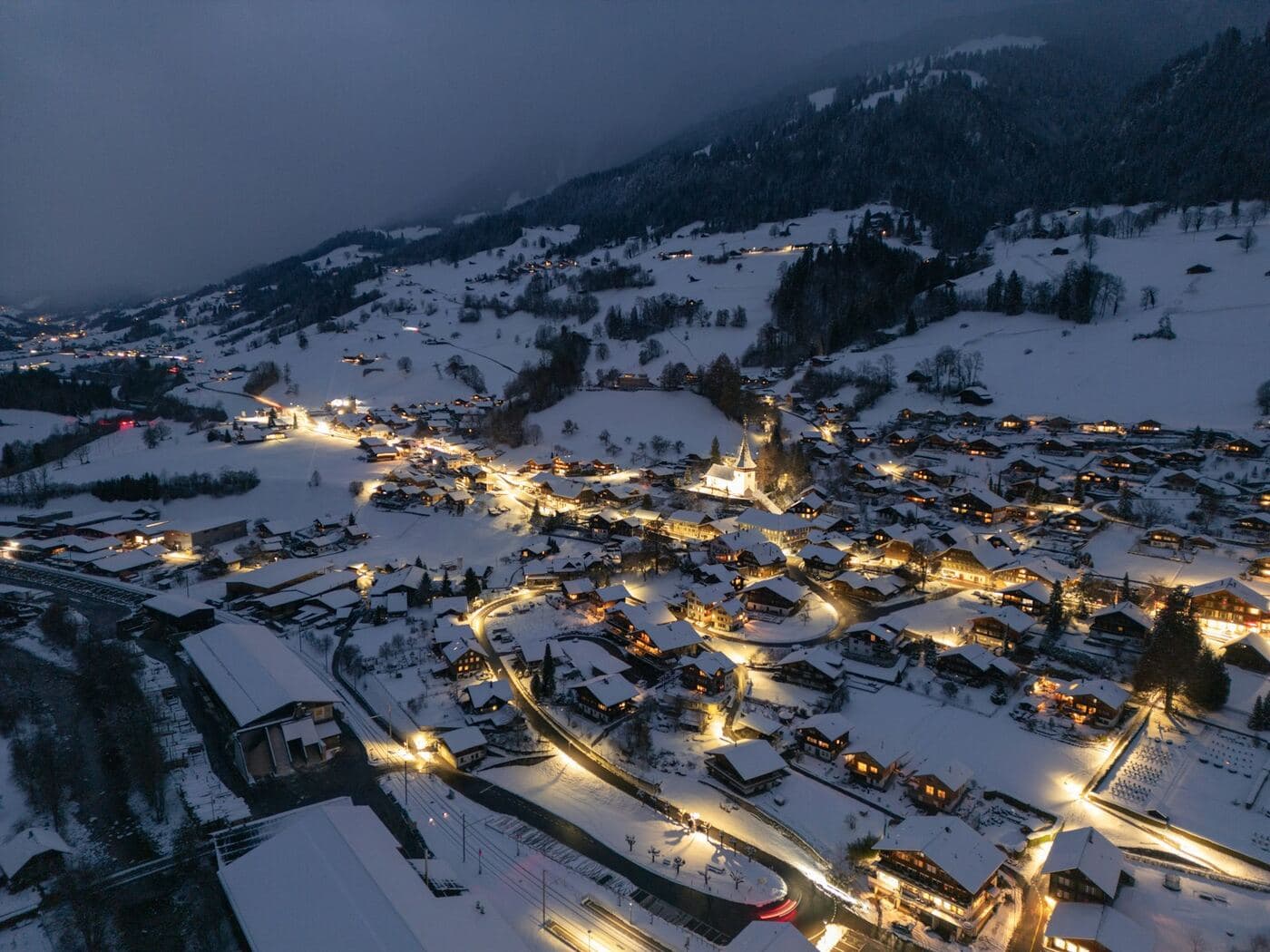 An alpine village lit up at dusk in the snow